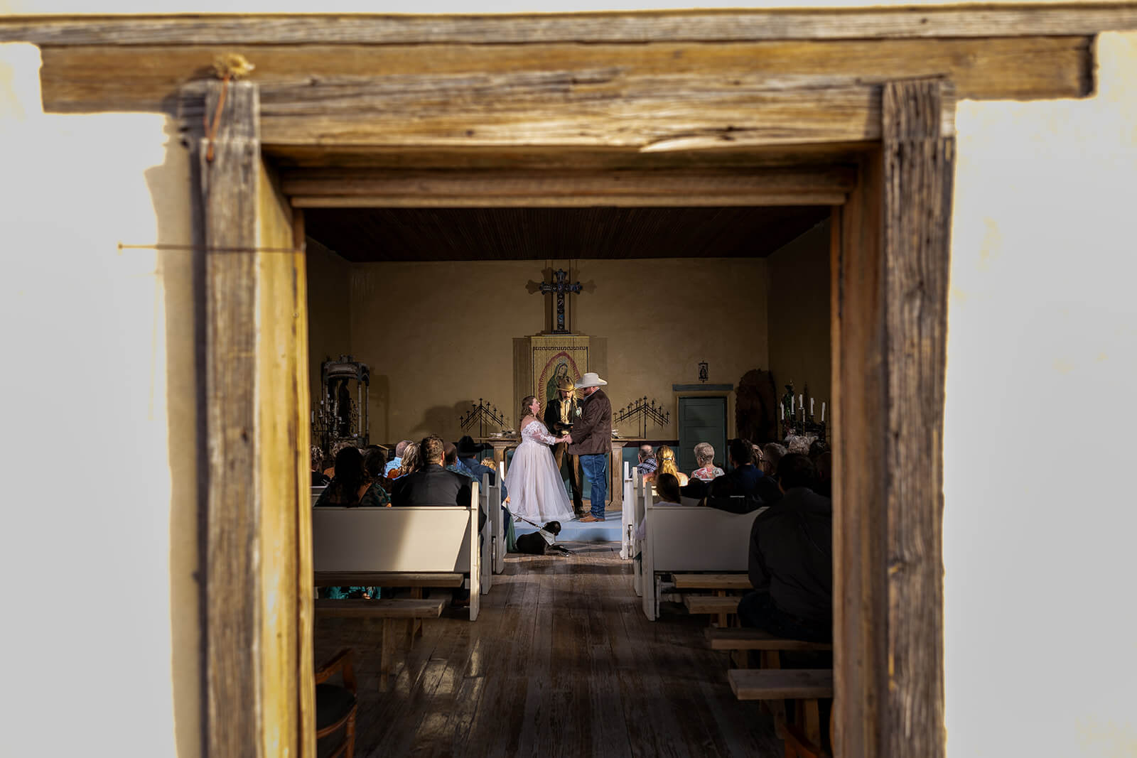 Wedding inside Saint Agnes Couple moments away from saying I Do in Saint Agnes Church in Terlingua Ghost Town, Texas with friends and family in the pews witnessing this love story.